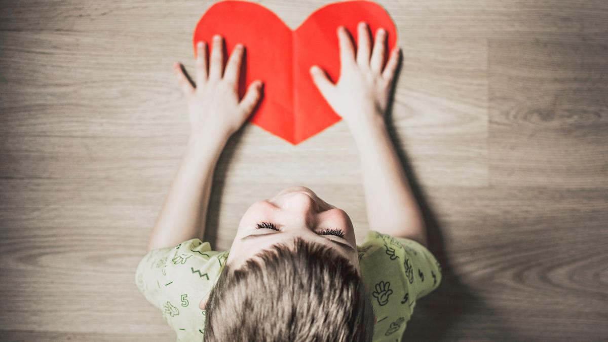 photo looking down above a child's head to a red heart on the floor
