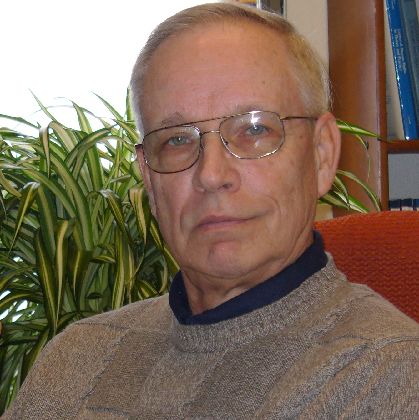 David Forsythe sitting in his office in front of the window and pot plant.