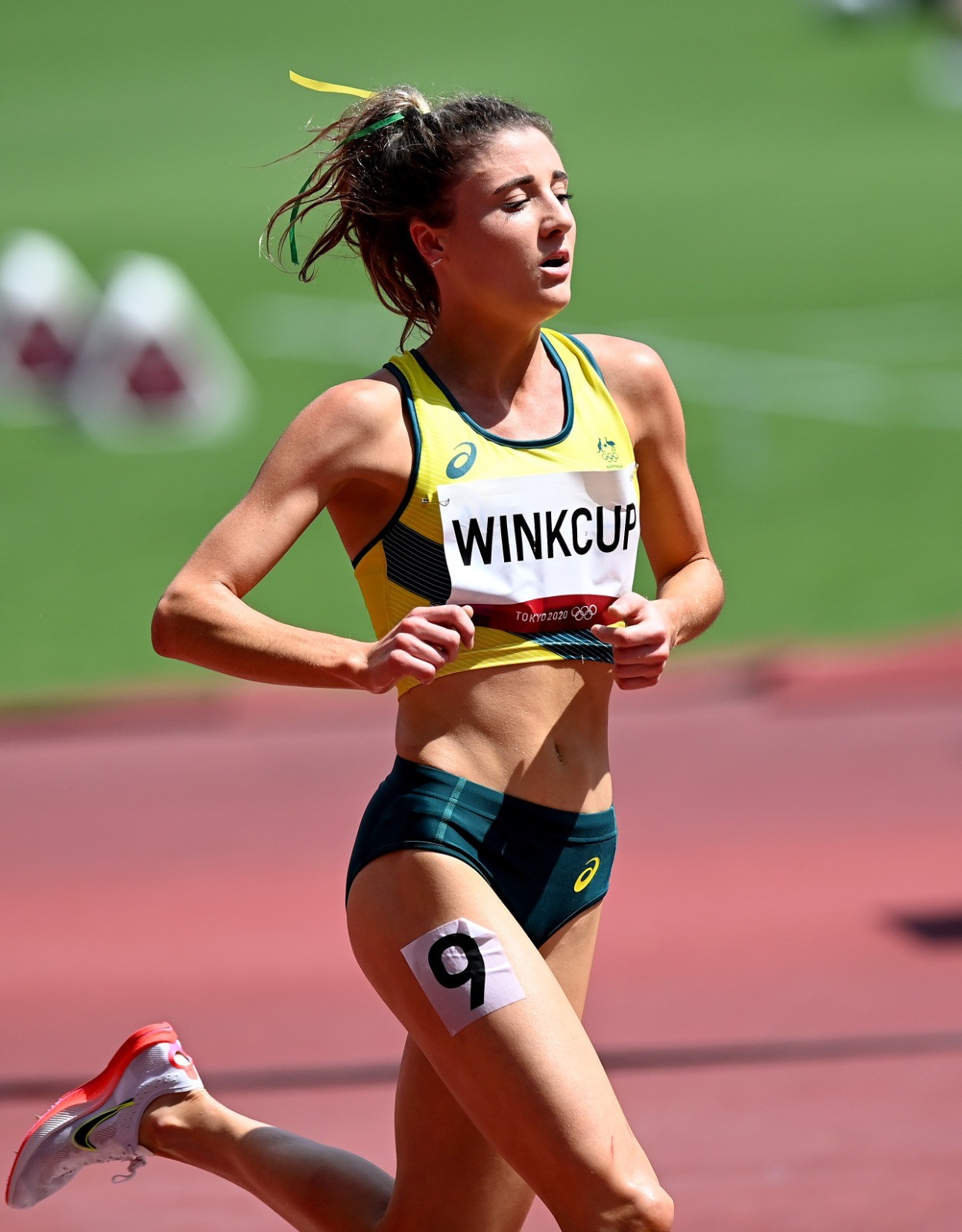 Young woman running on a track in the Australian Olympic Athletics uniform