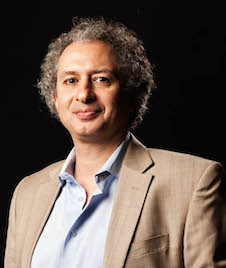 man with curly hair starring at camera, black background