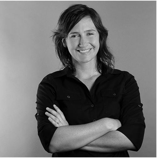 Black and white photo, with woman smiling at camera with arms crossed