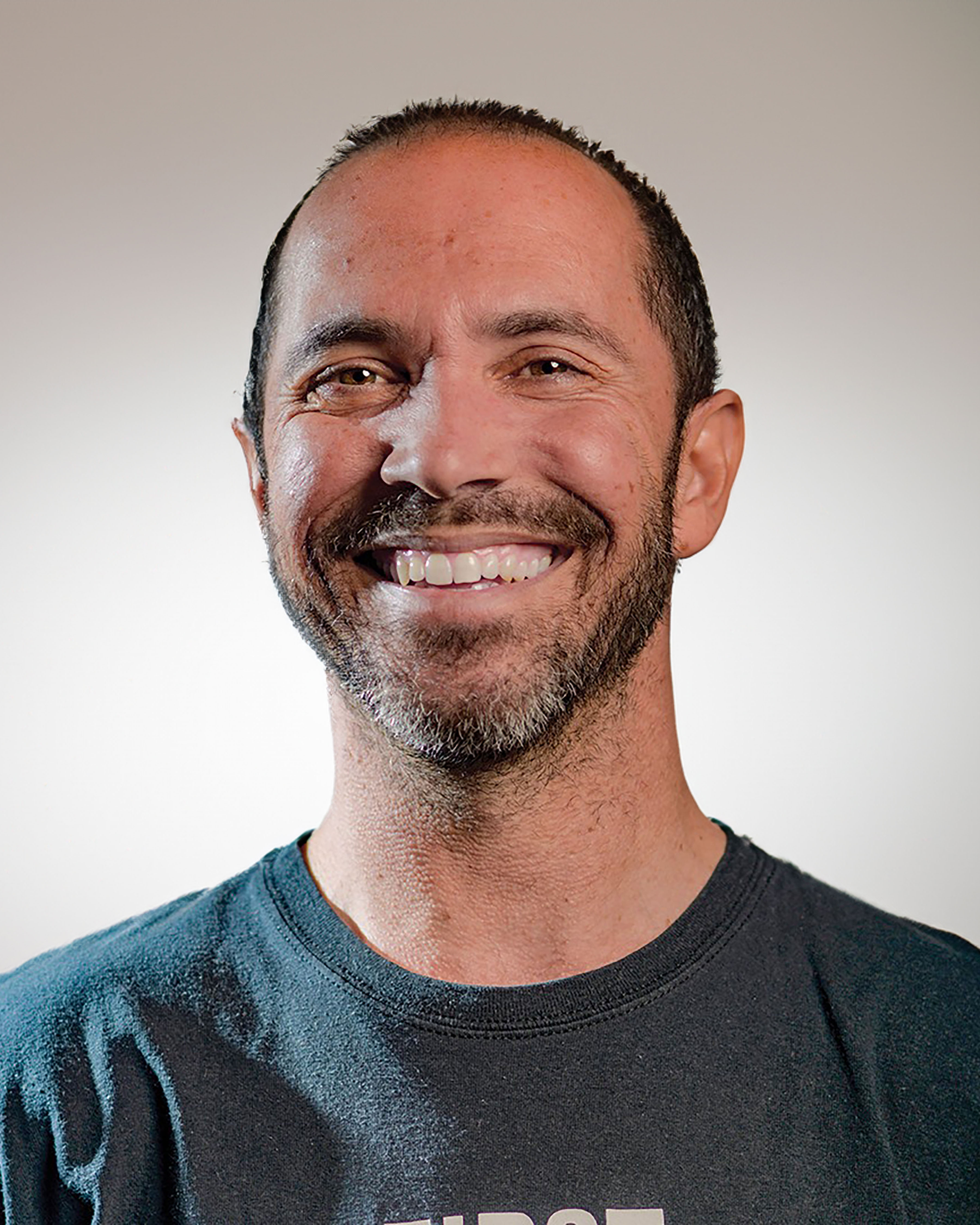 Portrait of artist Raymond Zada on a grey background.