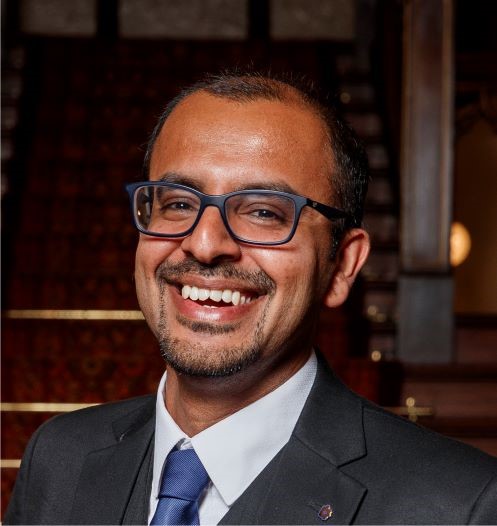 Neeraj smiling to the camera in a softly lit setting