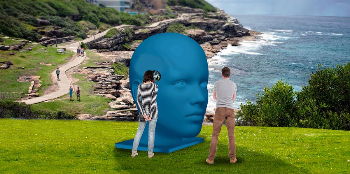 People looking at a sculpture of a blue head overlooking the sea