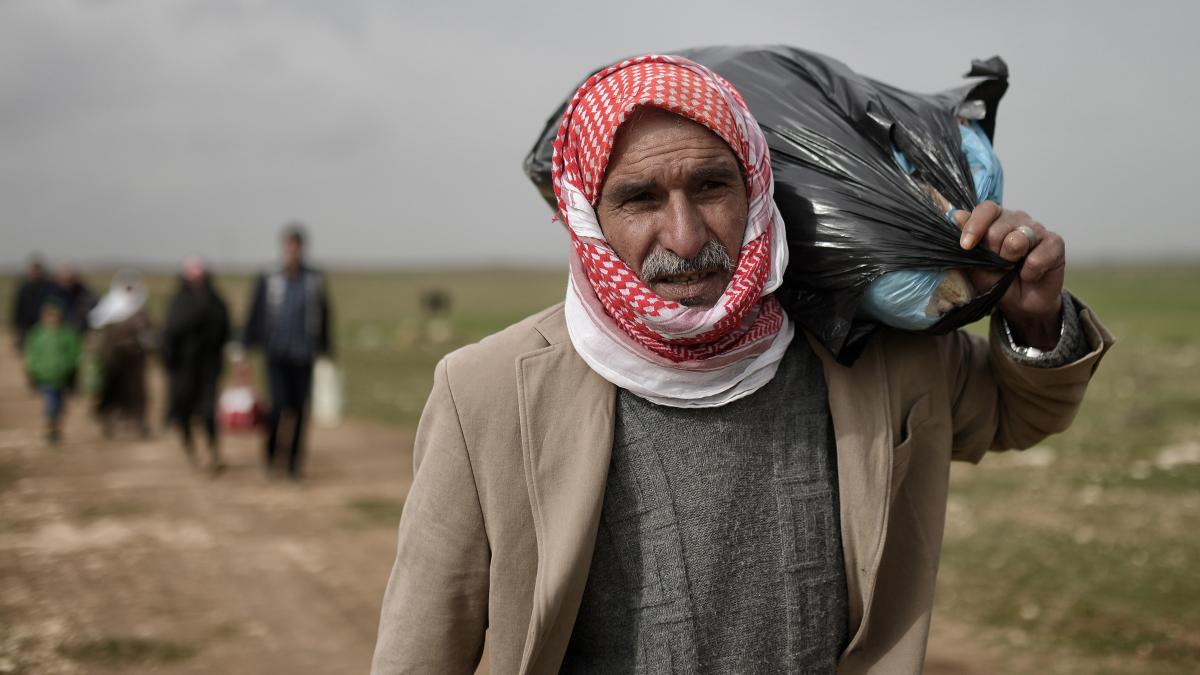 photo of refugee walking carry belonings over sholder