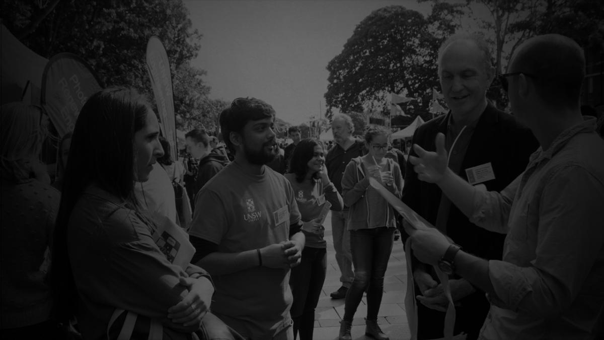 black and white image of students speaking to lecturers, casual setting outdoors