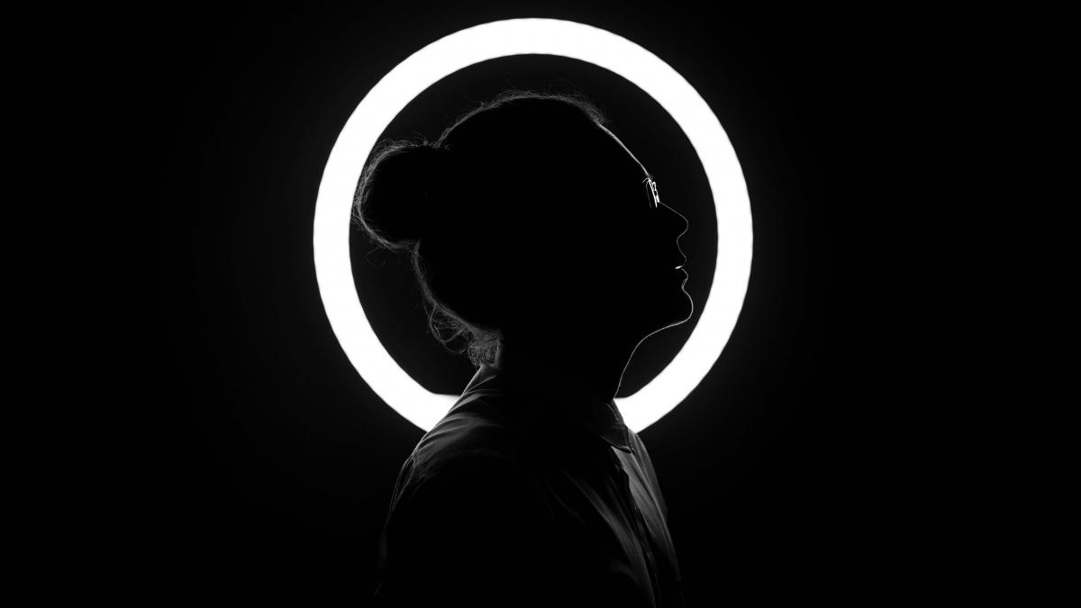 black and white photo of a women silhouette in front of a white circle with a black background