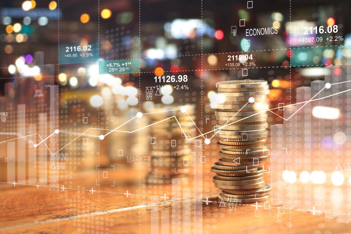 stock photo of pile of coins against a city background with graphs
