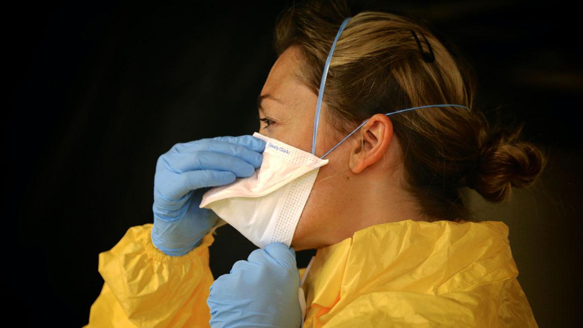 photo of a women in hazmat clothing, gloves and mask