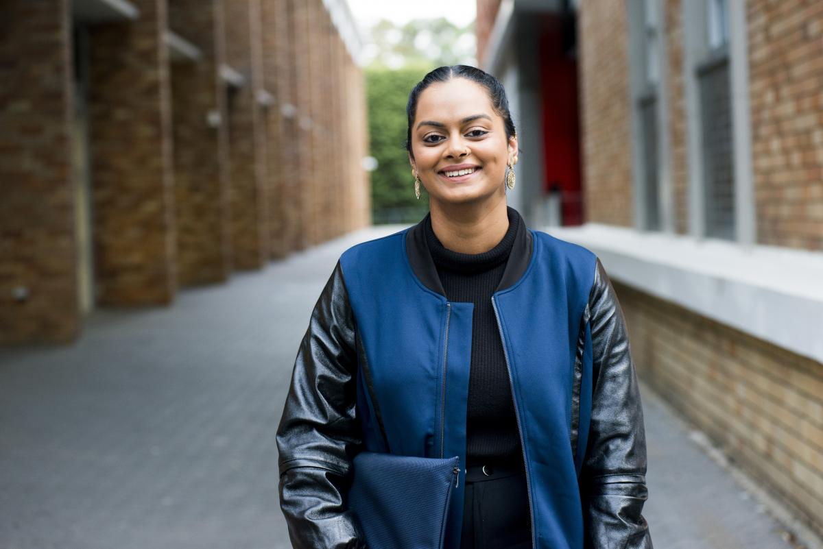 Photo of a young women smiling at the camera in a laneway