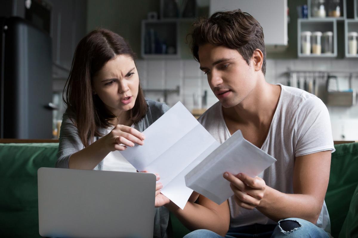 couple angry with financial problems looking at bills over laptop