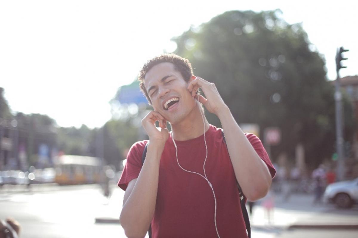 Young man in the street wearing headphones with his eyes closed while singing