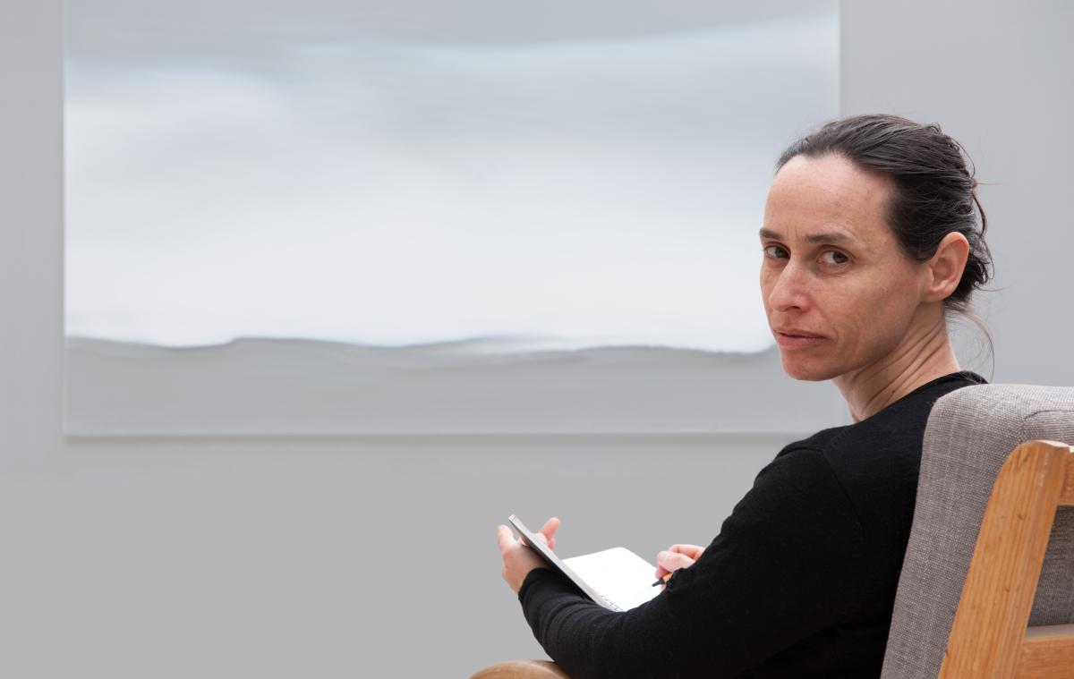 Jessica Loughlin sits in chair with traces of light 2016 in background