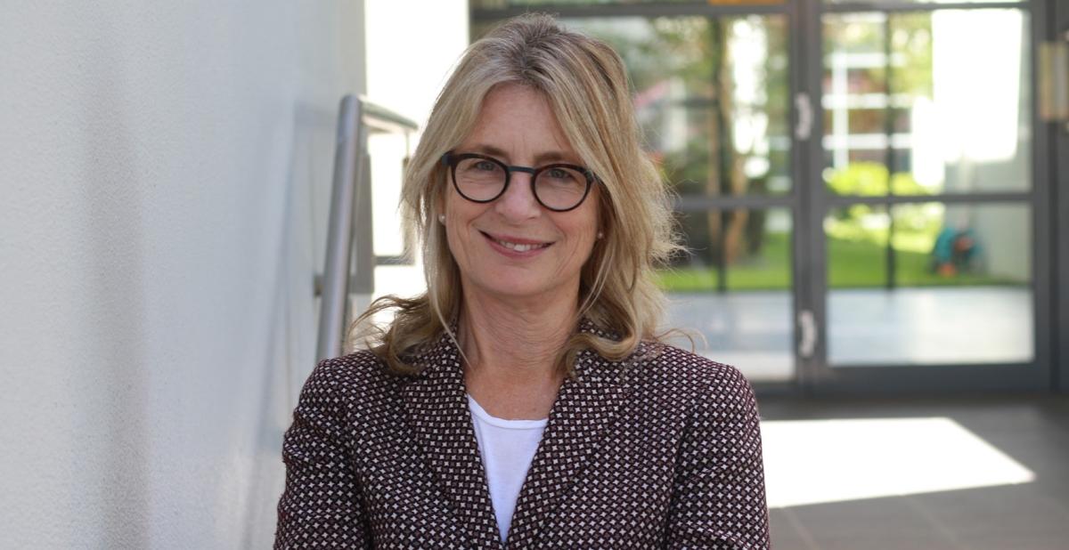 Professor Helen Christensen wearing a tweed jacket and reading glasses headshot