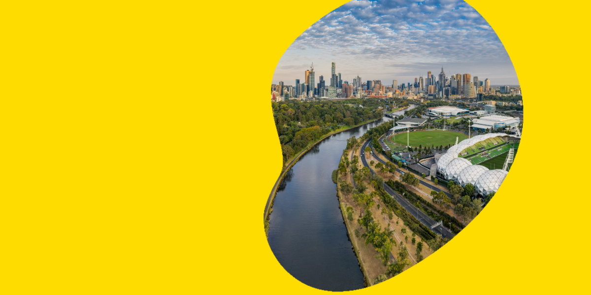 An aerial photo shows Melbourne Park in the soft light of sunset, with the Melbourne skyline twinkling in the background. 