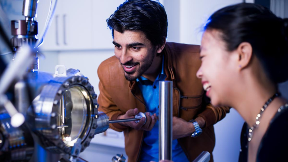 2 people looking at some equipment and smiling
