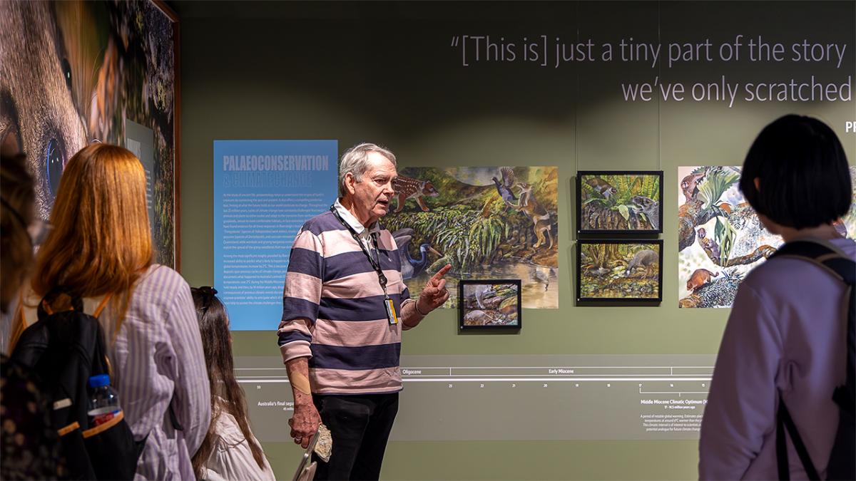 A man in an exhibition space explaining something while holding a specimen