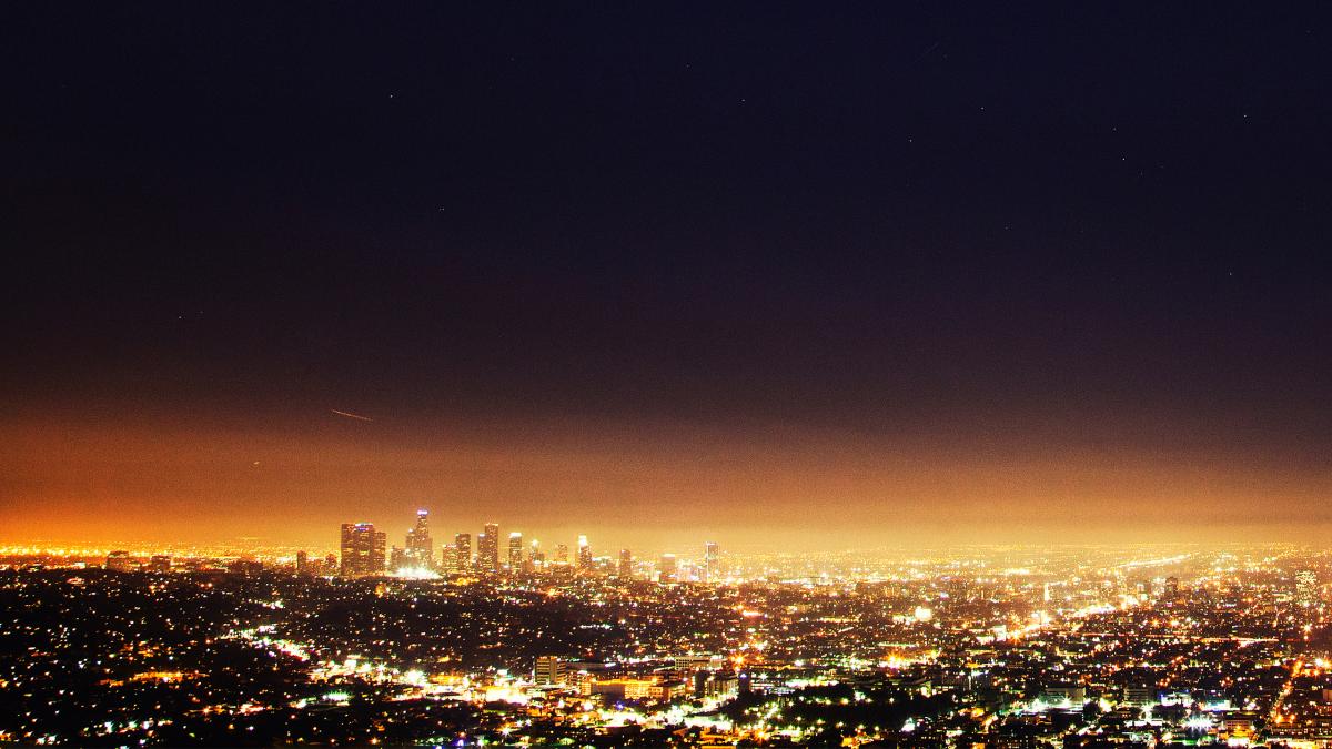 A vast city skyline glowing with bright lights at night under a dark sky.