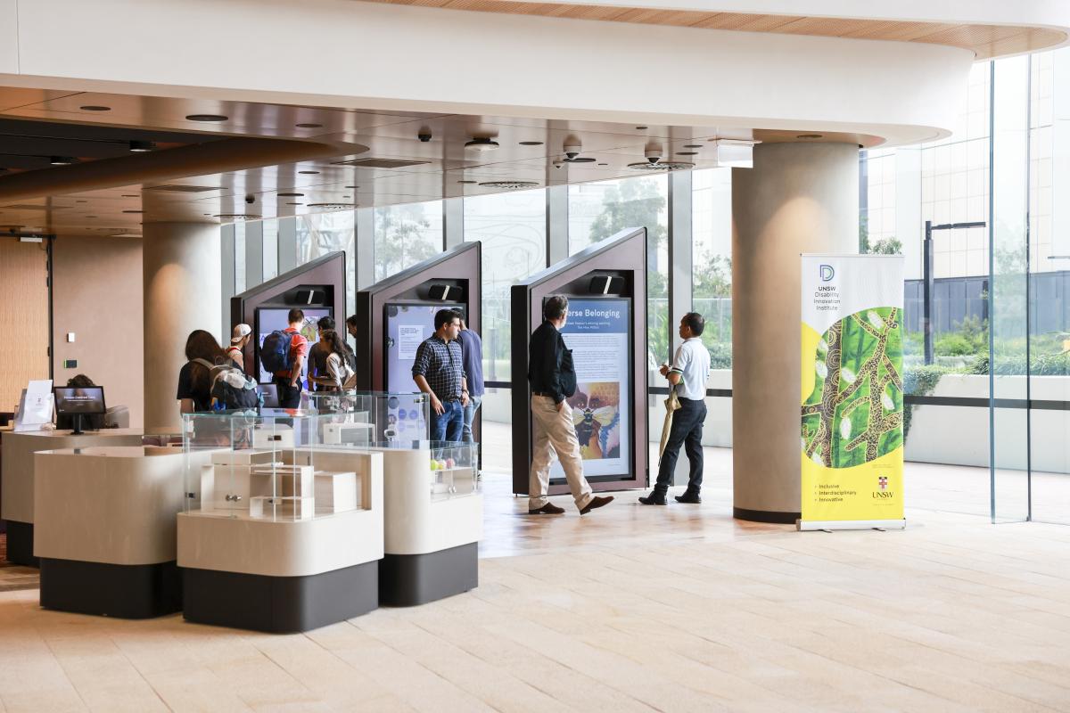 People walking in a hall with digital screen displays